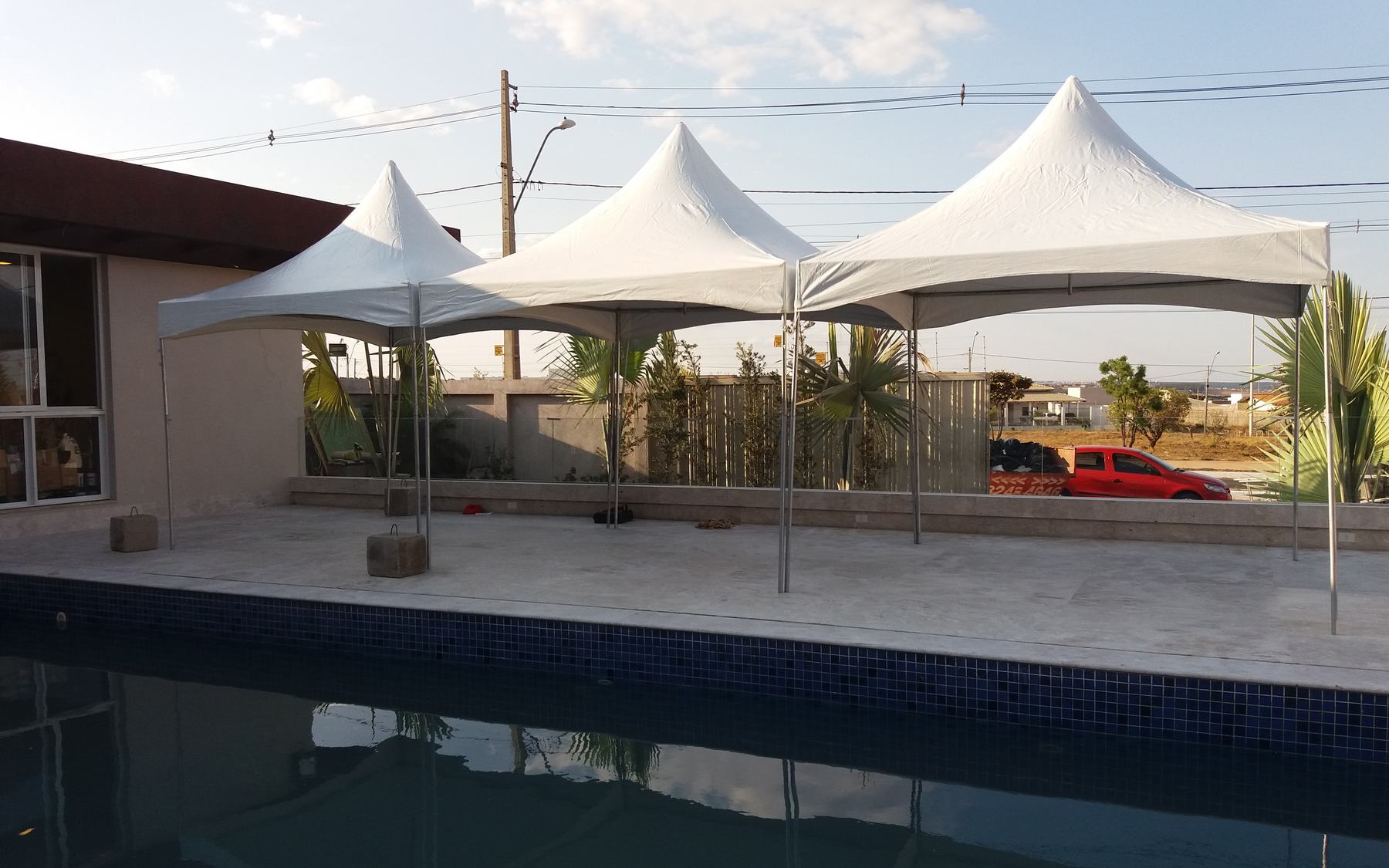 Três tendas chapéu de bruxa brancas da Mestre Tendas montadas na área de piscina de uma casa em Brasília-DF